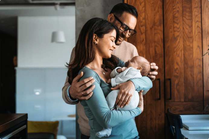 Parents smiling and embracing their newborn baby
