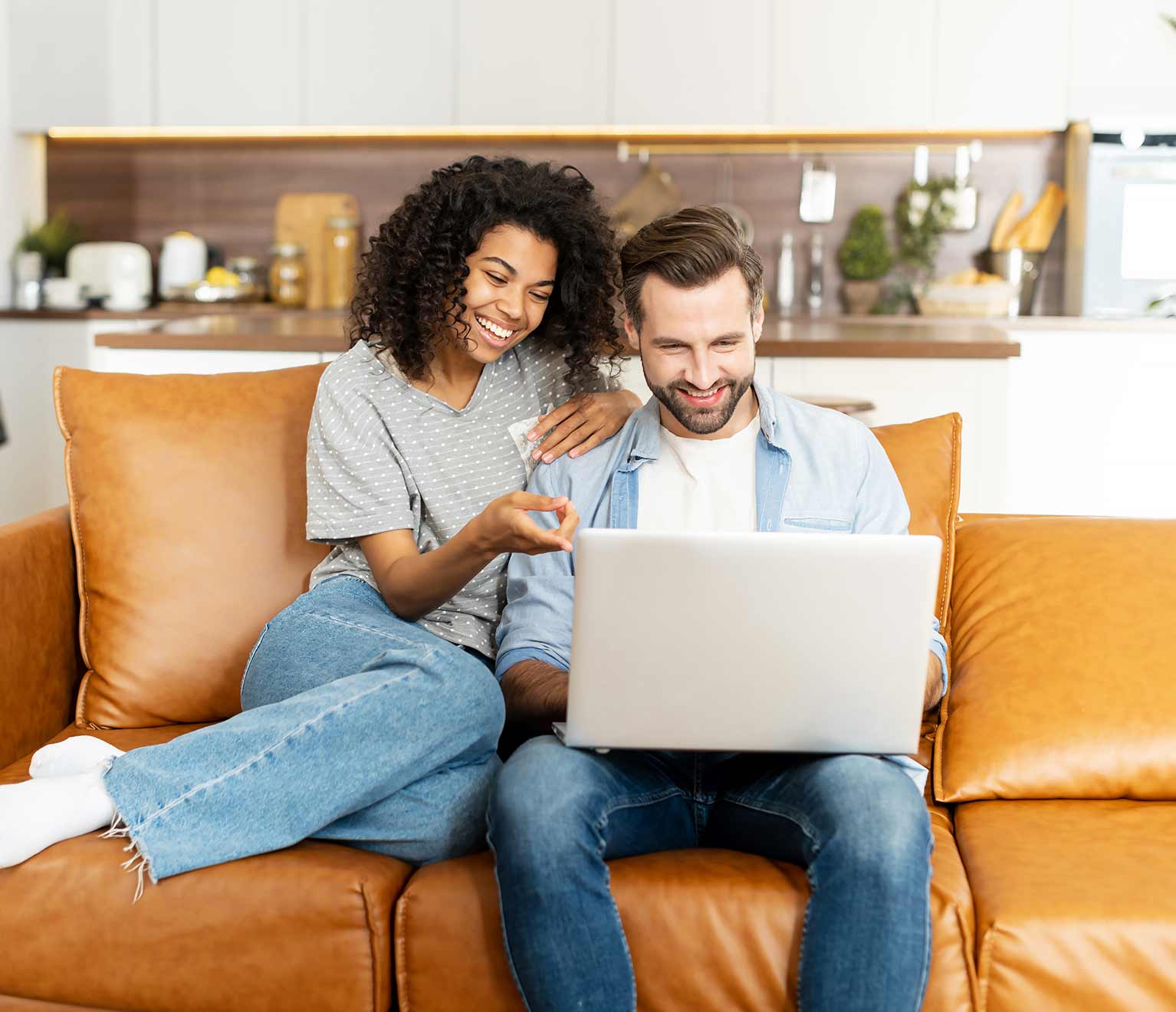 Young couple sitting on couch customizing home insurance online.