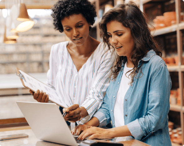 Two businesspeople standing behind a desk working on a laptop.